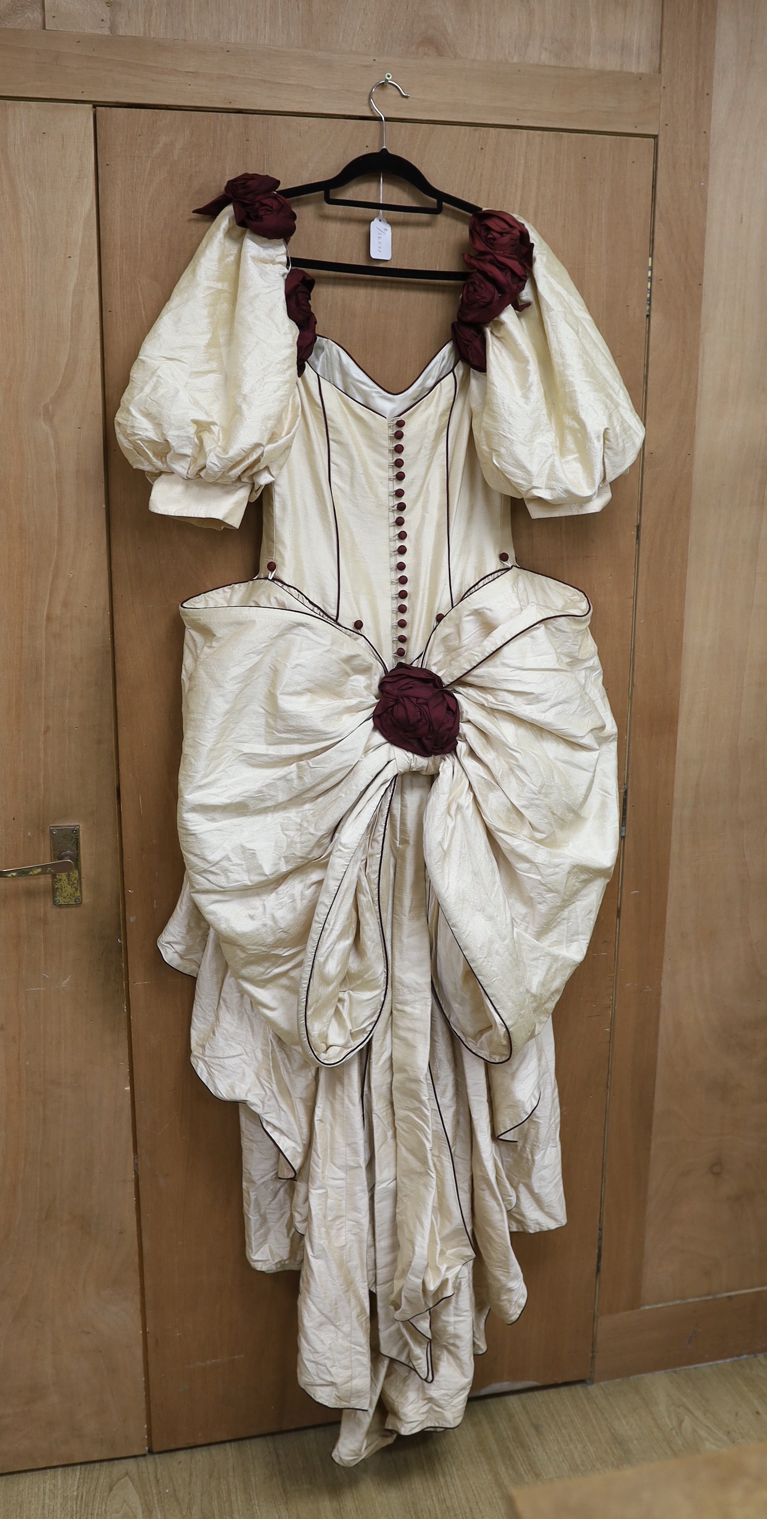 A late 20th century cream silk and burgundy trimmed gown, with bustle, possibly operatic or theatrical